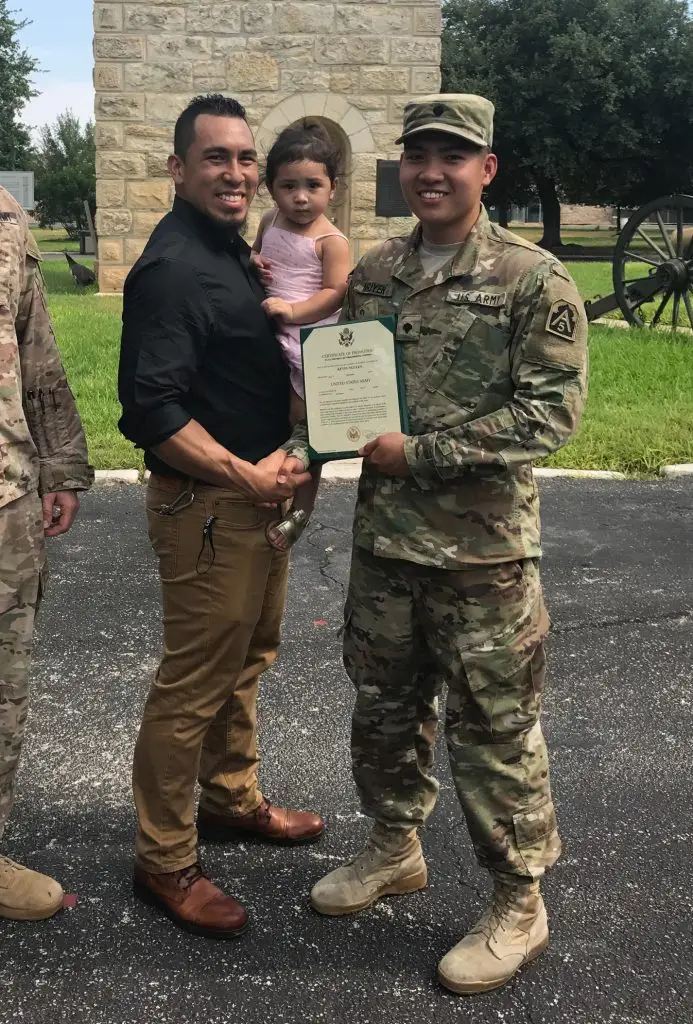 Kevin Nguyen standing in front of the Alamo Monument holding a certiicate